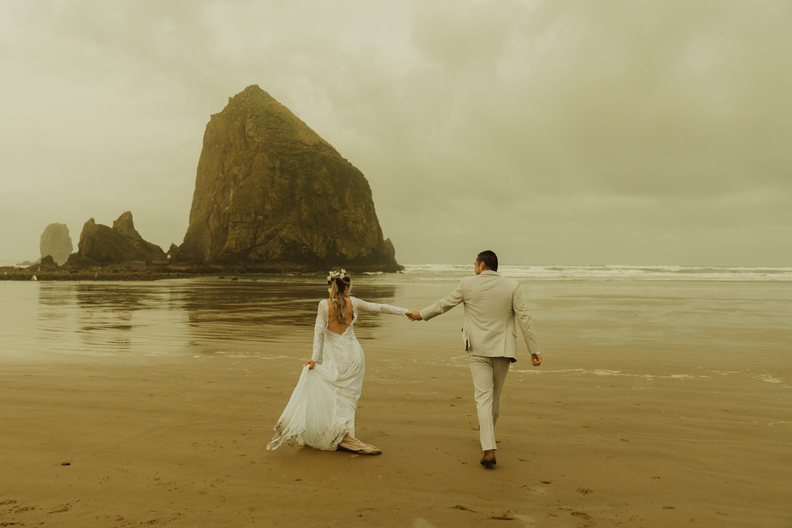 Couple running on cannon beach Oregon coast during their elopement and bridal session